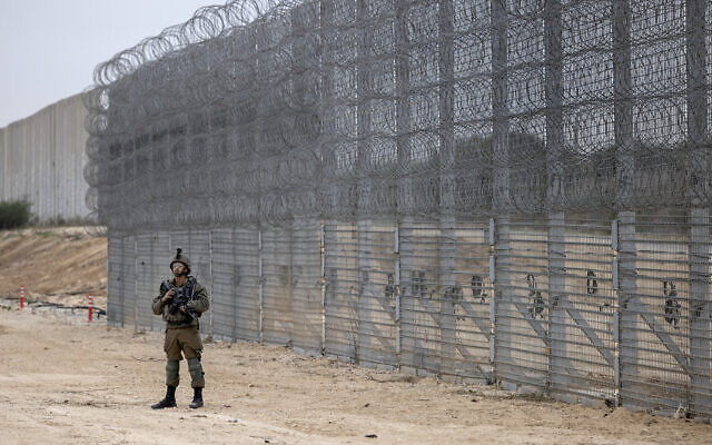 An Israeli soldier stands guard during a ceremony opening the newly completed barrier above and below the Israel-Gaza border, December 7, 2021.  (AP Photo/Tsafrir Abayov)