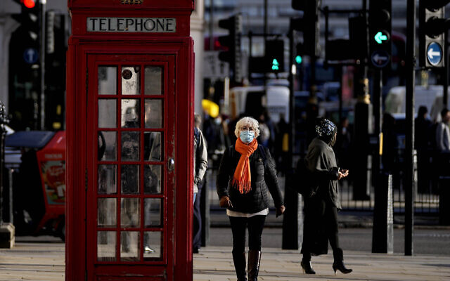 People wear face coverings as they walk through Westminster, in London, Thursday, Dec. 9, 2021. British Prime Minister Boris Johnson has announced tighter restrictions to stem the spread of the omicron variant. He is again urging people to work from home and mandating COVID-19 passes to get into nightclubs and large events. (AP Photo/Frank Augstein)