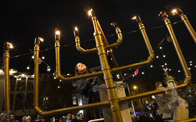 Rabbanit Dasi Fruchter, of the South Philadelphia Shtiebel, lights a menorah during a public Hanukkah celebration and menorah lighting ceremony in South Philadelphia, on Sunday, December 5, 2021. (AP Photo/Ryan Collerd)