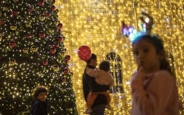 People walk past a Christmas decorated church in Haifa, Israel, Wednesday, Dec. 15, 2021. (AP/Ariel Schalit)