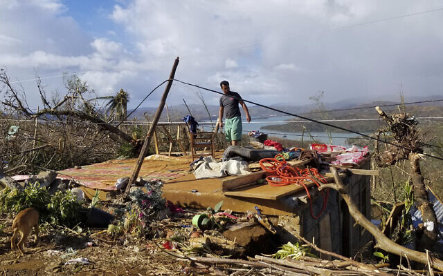A man checks his damaged home due to Typhoon Rai at Dinagat islands, southern Philippines on December 19, 2021. The death toll continues to rise following the strongest typhoon to batter the Philippines this year, with several central towns and provinces still grappling with downed communications and power outages and pleading for food and water, officials said Monday. (Office of the Vice President via AP)