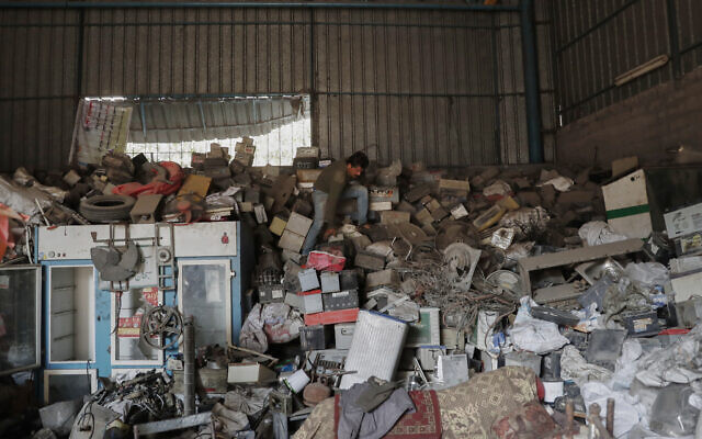 A Palestinian worker looks for batteries among other electric waste at a warehouse in Jebaliya, Gaza Strip, December 15, 2021. (AP Photo/Adel Hana)
