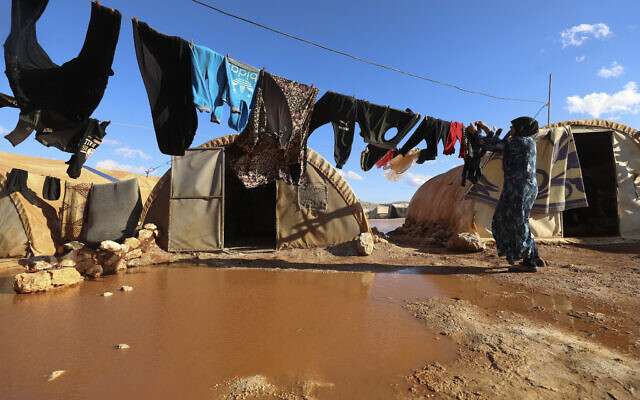 A woman hangs laundry in a flooded refugee camp in Idlib province, Syria, December 21, 2021. (AP Photo/Ghaith Alsayed)