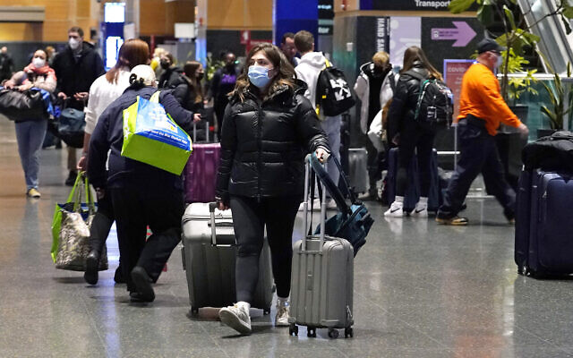 Travelers trek through Terminal E at Logan Airport, on Tuesday, December 21, 2021, in Boston. (AP Photo/Charles Krupa)