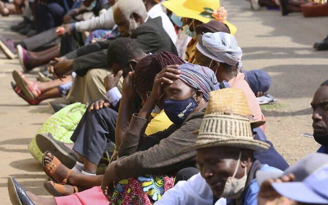 Elderly people, many without face masks or not fitted properly, sit in tightly packed lines waiting to withdraw their pensions in Harare, Zimbabwe on December 13, 2021. (AP Photo/ Tsvangirayi Mukwazhi)