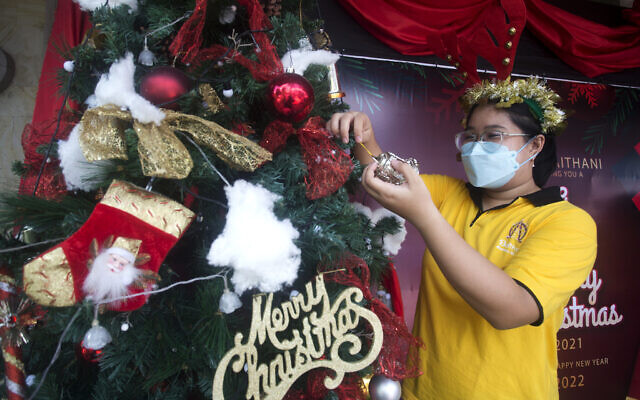 A woman prepares a Christmas tree decoration at a church in Bali, Indonesia on, Dec. 24, 2021. (AP Photo/Firdia Lisnawati)