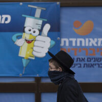 An ultra-Orthodox Jewish youth walks past a coronavirus vaccination center, in Jerusalem, Dec. 22, 2021 (AP Photo/Oded Balilty)