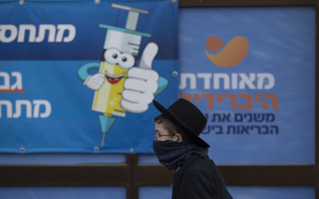 An ultra-Orthodox Jewish youth walks past a coronavirus vaccination center, in Jerusalem, Dec. 22, 2021 (AP Photo/Oded Balilty)