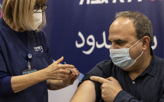 A staffer at the Sheba Medical Center receives a fourth dose of the Pfizer-BioNTech COVID-19 vaccine, in Ramat Gan, Israel, Monday, Dec. 27, 2021. (AP Photo/Tsafrir Abayov)