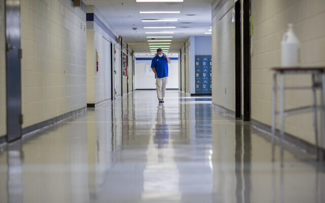 A middle school principal walks the empty halls of his school as he speaks with one of his teachers to get an update on her COVID-19 symptoms, Friday, Aug., 20, 2021, in Wrightsville, Ga. (AP Photo/Stephen B. Morton, File)