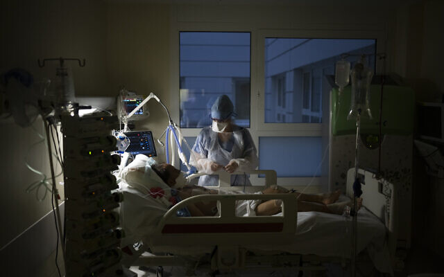 A nurse watches over a COVID-19 patient on a ventilator in the an intensive care unit at the la Timone hospital in Marseille, southern France, December 31, 2021. (AP Photo/Daniel Cole)