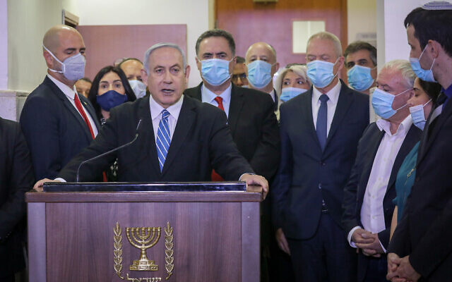 Then-prime minister Benjamin Netanyahu, surrounded by Likud lawmakers, gives a televised statement before the start of his corruption trial at the Jerusalem District Court on May 24, 2020. (Yonatan Sindel/Flash90)