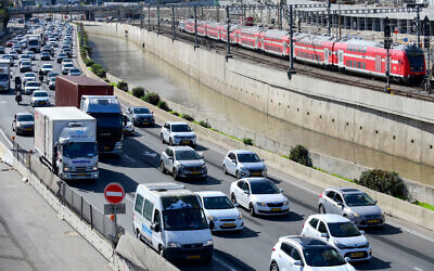Traffic jams the Ayalon highway in Tel Aviv, as a train passes above, December 2, 2021 (Tomer Neuberg/Flash90)