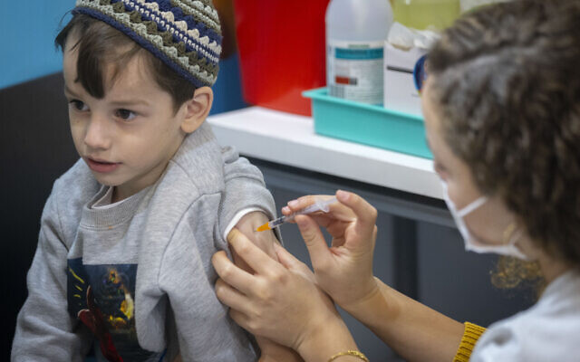 A child receives a dose of the COVID-19 vaccine, at a Clallit vaccine center in Jerusalem on December 21, 2021. (Olivier Fitoussi/Flash90)