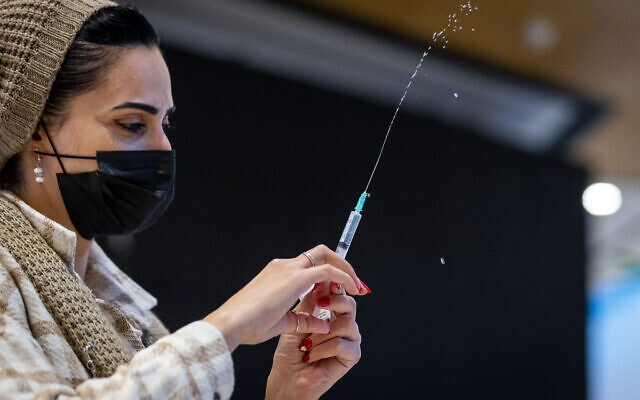 A nurse administers a dose of the coronavirus vaccine at a pop-up Health Ministry vaccine center at the Malcha mall in Jerusalem, on December 23, 2021. (Olivier Fitoussi/Flash90)
