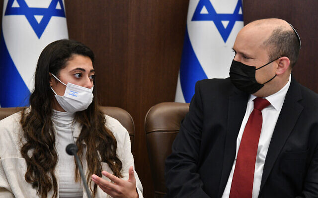 Prime Minister Naftali Bennett, right, with Michal Zehut, a teenage girl suffering from ‘long-COVID’ symptoms after recovering from the coronavirus, seen during the cabinet meeting in Jerusalem, December 19, 2021. (Haim Zach/GPO)