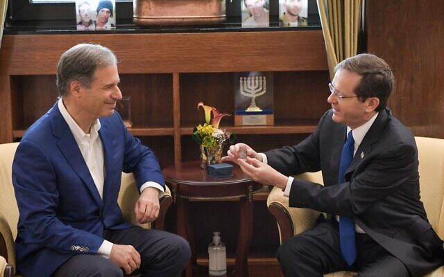 President Isaac Herzog, left, presents Israeli astronaut Eytan Stibbe with a glass cube inscribed with a prayer for the welfare of the State of Israel, at the president's residence in Jerusalem, December 16, 2021. (Kobi Gideon/GPO)