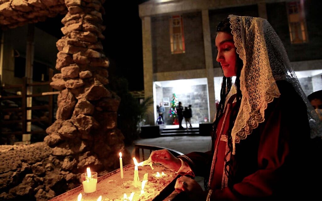 An Iraqi Christian woman lights candles during a Christmas Eve Mass in St. Teresa's Church ahead of Christmas celebrations, in Basra, Iraq, December 24, 2021. (AP Photo/Nabil al-Jurani)