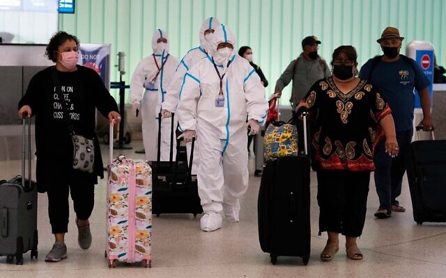 Air China flight crew members in hazmat suits walk through the arrivals area at Los Angeles International Airport in Los Angeles, Nov. 30, 2021. (AP Photo/Jae C. Hong)