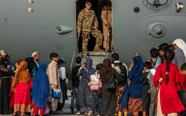 Afghan refugees prepare to board a plane at Al Udeid Air Base, Qatar, August 22, 2021. (Airman 1st Class Kylie Barrow/U.S. Air Force via AP)