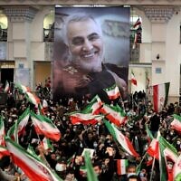 Iranians lift national flags during a ceremony in the capital Tehran, on January 3, 2022, commemorating the second anniversary of the killing in Iraq of top Iranian commander Qassem Soleimani (portrait) and Iraqi commander Abu Mahdi al-Muhandis in a US raid. (Atta Kenare/AFP)