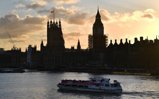 A Thames river cruise boat passes as the sun sets behind the Palace of Westminster in London, on January 5, 2022. (Justin Tallis/AFP)