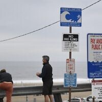 People stretch next to a tsunami hazard zone sign in El Segundo, California, on January 15, 2022. (Patrick T. Fallon/AFP)