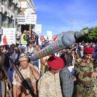 Supporters of Yemen's Iran-backed Houthi rebels carry a mock rocket as they demonstrate in the capital Sanaa to denounce a reported airstrike by the Saudi-led coalition on a prison in the country's rebel-held north, on January 21, 2022. (Mohammed Huwais/AFP)