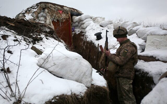 A Ukrainian serviceman checks his weapon as he stands in a trench on the frontline with Russia-backed separatists near Zolote village, in the eastern Lugansk region, on January 21, 2022.(Anatolii Stepanov/AFP)