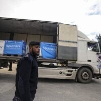 A Palestinian security officer stands next to a truck carrying Sputnik V vaccines, donated by the United Arab Emirates, at a cold storage warehouse in Gaza City on January 26, 2022. (Mahmud HAMS / AFP)