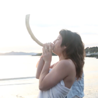 Rebecca Erev, co-founder of the Queer Mikveh Project, blows the shofar at the first QMP mikveh event at the Albany Bulb in Albany, California, in 2015. (Chani Bockwinkel/ via JTA)