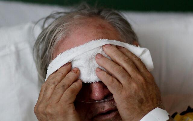 Illustrative image: a patient battling influenza, placing a cold compress on his head. (AP Photo/David Goldman)