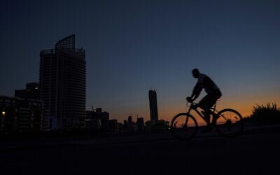 A man rides his bike along the seaside promenade as the capital city remains in darkness during a power outage, in Beirut, Lebanon, on Thursday, August 19, 2021. (AP Photo/ Hassan Ammar)
