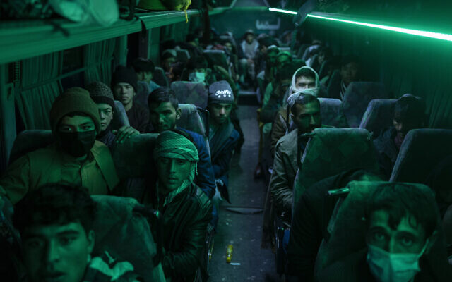 Afghan men sit in a bus in Herat, Afghanistan, on November 22, 2021, for a 300-mile trip south to Nimrooz near the Iranian border. (AP Photo/Petros Giannakouris)