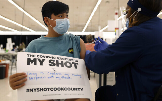 Illustrative: Lucas Kittikamron-Mora, 13, holds a sign in support of COVID-19 vaccinations as he receives his first Pfizer vaccination at the Cook County Public Health Department, May 13, 2021, in Des Plaines, Illinois. (AP Photo/ Shafkat Anowar, file)
