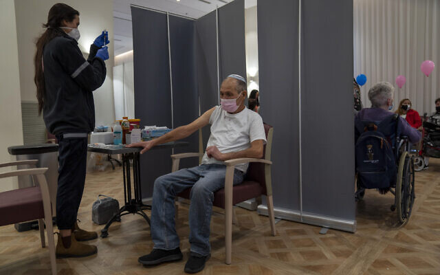 A man receives a fourth Pfizer-BioNTech COVID-19 vaccine at a private nursing home, in Netanya, on January 5, 2022. (AP Photo/Ariel Schalit)