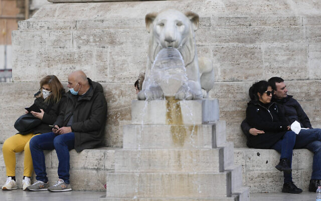 People sit by the Rome's Piazza del Popolo Lions fountain, Wednesday, Jan. 5, 2022 (AP Photo/Gregorio Borgia)