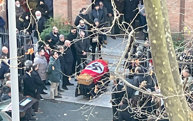 A picture made available by the Italian online news portal Open, showing people gathered around a swastika-covered casket outside the St. Lucia church, in Rome, on Monday, January 10, 2022. (Open Via AP)