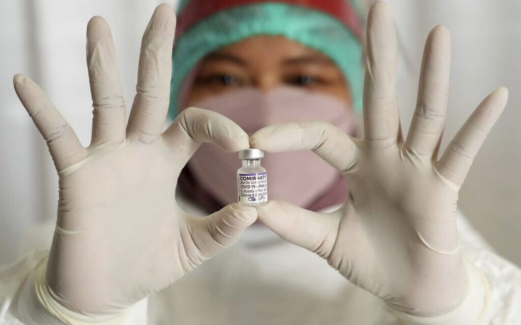 As part of the global race to vaccinate against COVID-19, a medical worker at South Tangerang Regional General Hospital in Tangerang, Indonesia, holds a vaccine vial the she is using to administer third doses on, Jan. 12, 2022. (AP Photo/Tatan Syuflana)