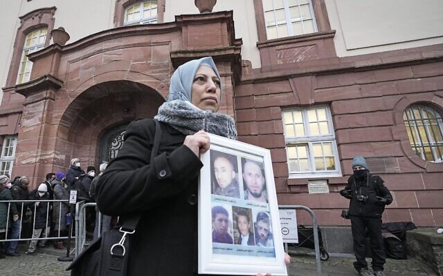 Syrian woman Yasmen Almashan holds the pictures of her five brothers killed in Syria before the verdict in front of the court in Koblenz, Germany, Thursday, Jan. 13, 2022. (AP Photo/Martin Meissner)