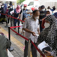 People line up to register for a booster shot of Pfizer COVID-19 vaccine at a community health center in Jakarta, Indonesia, January 17, 2022. (AP Photo/Achmad Ibrahim)