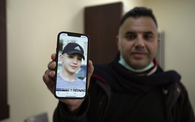 Muamar Nakhleh, father of Amal Nakhleh, a Palestinian teen with a rare neuromuscular disorder who has been held without charge for a year, shows his photo at his office in Ramallah, on January 10, 2022. (AP Photo/Majdi Mohammed)