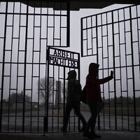People take photos as they enter the Sachsenhausen Nazi death camp through the gate with the phrase 'Arbeit macht frei' (work sets you free), in Oranienburg, about 30 kilometers (18 miles) north of Berlin, Germany, Tuesday, January 25, 2022. (AP/Markus Schreiber)