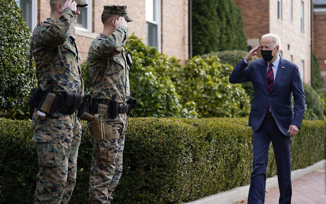 US President Joe Biden returns a salute as he walks by the Marine Barracks Washington after visiting the Honey Made store, Tuesday, Jan. 25, 2022, in Washington. (AP Photo/Andrew Harnik)