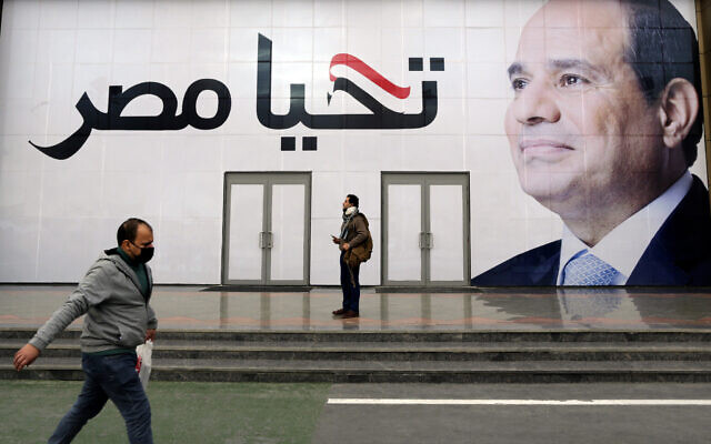 A man walks in front of a billboard for Egyptian President Egyptian President Abdel-Fattah el-Sissi, with Arabic that reads 'Long live Egypt,' at the annual Cairo International Book Fair, in Cairo, Egypt, Thursday, Jan. 27, 2022. (AP Photo/Amr Nabil)