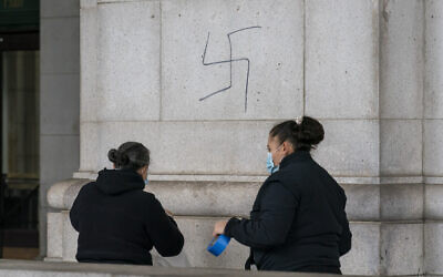 A cleaning crew prepares to cover hand-drawn swastikas on the front of Union Station near the US Capitol in Washington, on January 28, 2022. (AP Photo/J. Scott Applewhite)