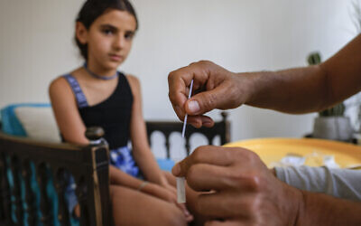 A Jerusalem father tests his daughter with a home rapid test ahead of her first day of school, August 31, 2021. (Olivier Fitoussi/Flash90)