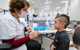 A child receives a COVID-19 vaccine, at Clalit vaccination center in Katzrin, Golan Heights, on December 16, 2021. (Michael Giladi/Flash90)