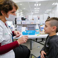 A child receives a COVID-19 vaccine, at Clalit vaccination center in Katsrin, Golan Heights, on December 16, 2021. (Michael Giladi/Flash90)