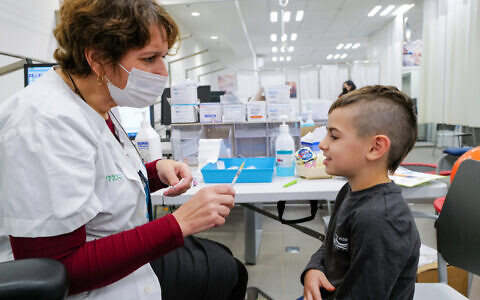 A child receives a COVID-19 vaccine, at Clalit vaccination center in Katsrin, Golan Heights, on December 16, 2021. (Michael Giladi/Flash90)